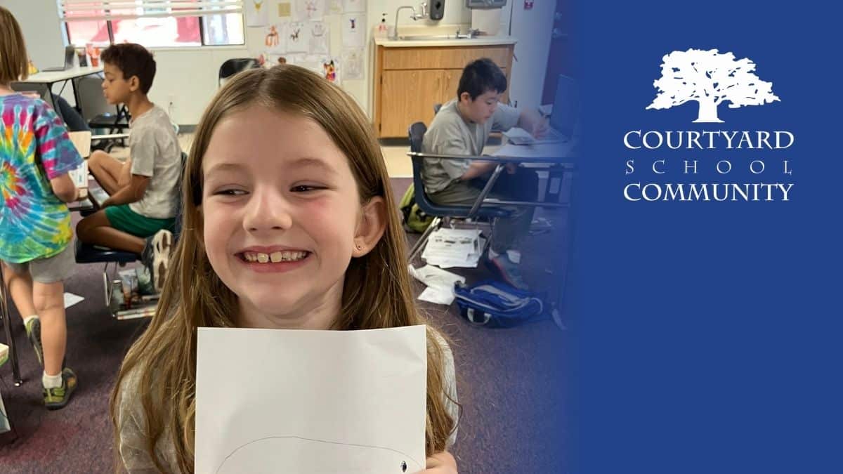 private elementary school in sacramento - girl holds up a drawing and smiles at the camera | Courtyard School