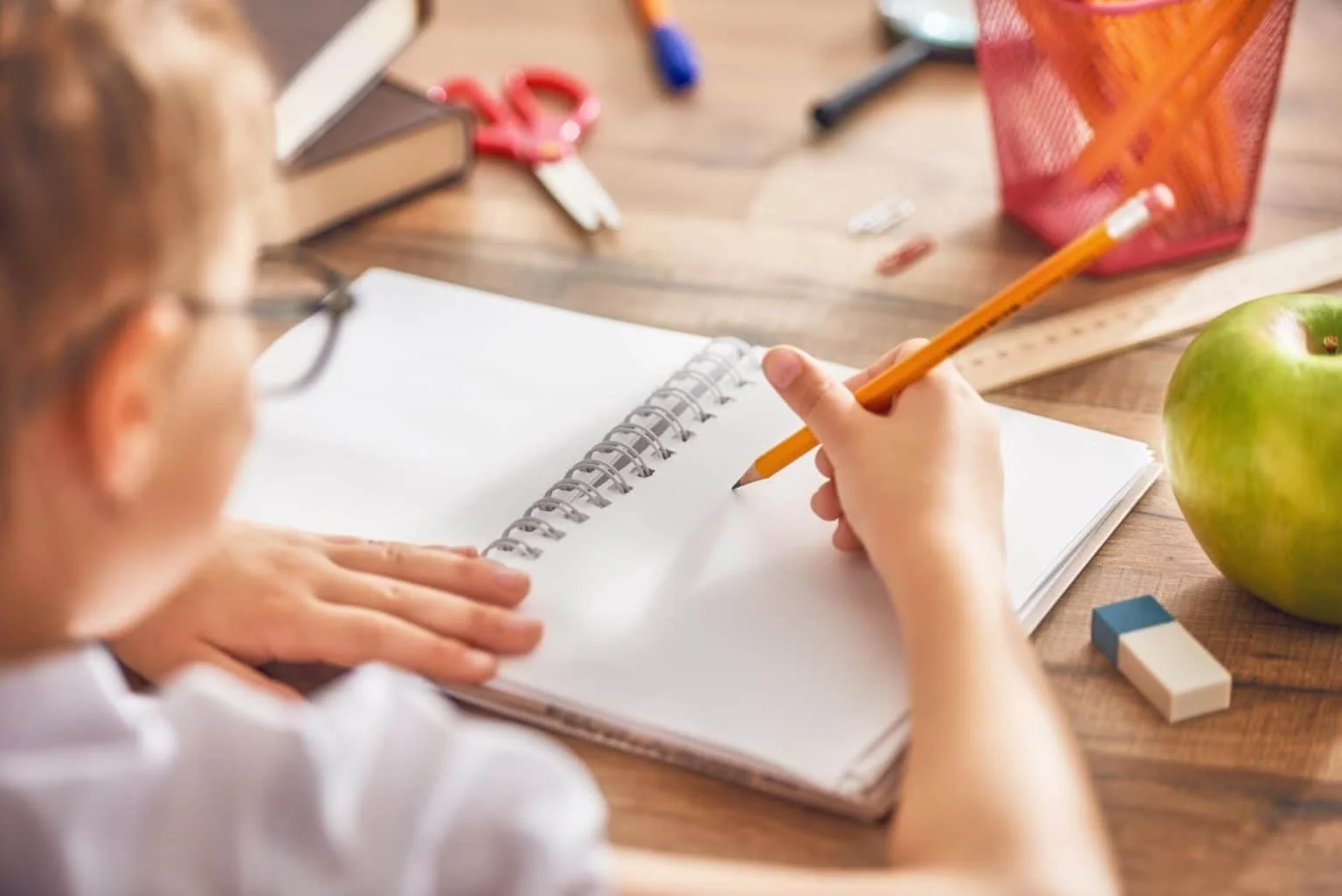 Back to school! Happy cute industrious child is sitting at a desk indoors. Kid is learning in class.